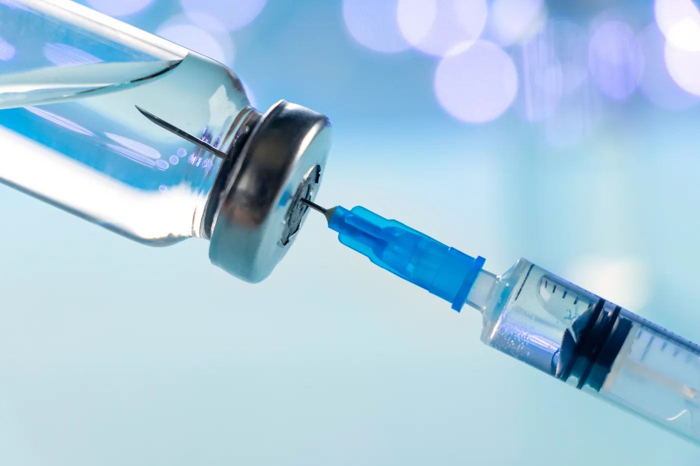 Syringe drawing vaccine from a glass vial