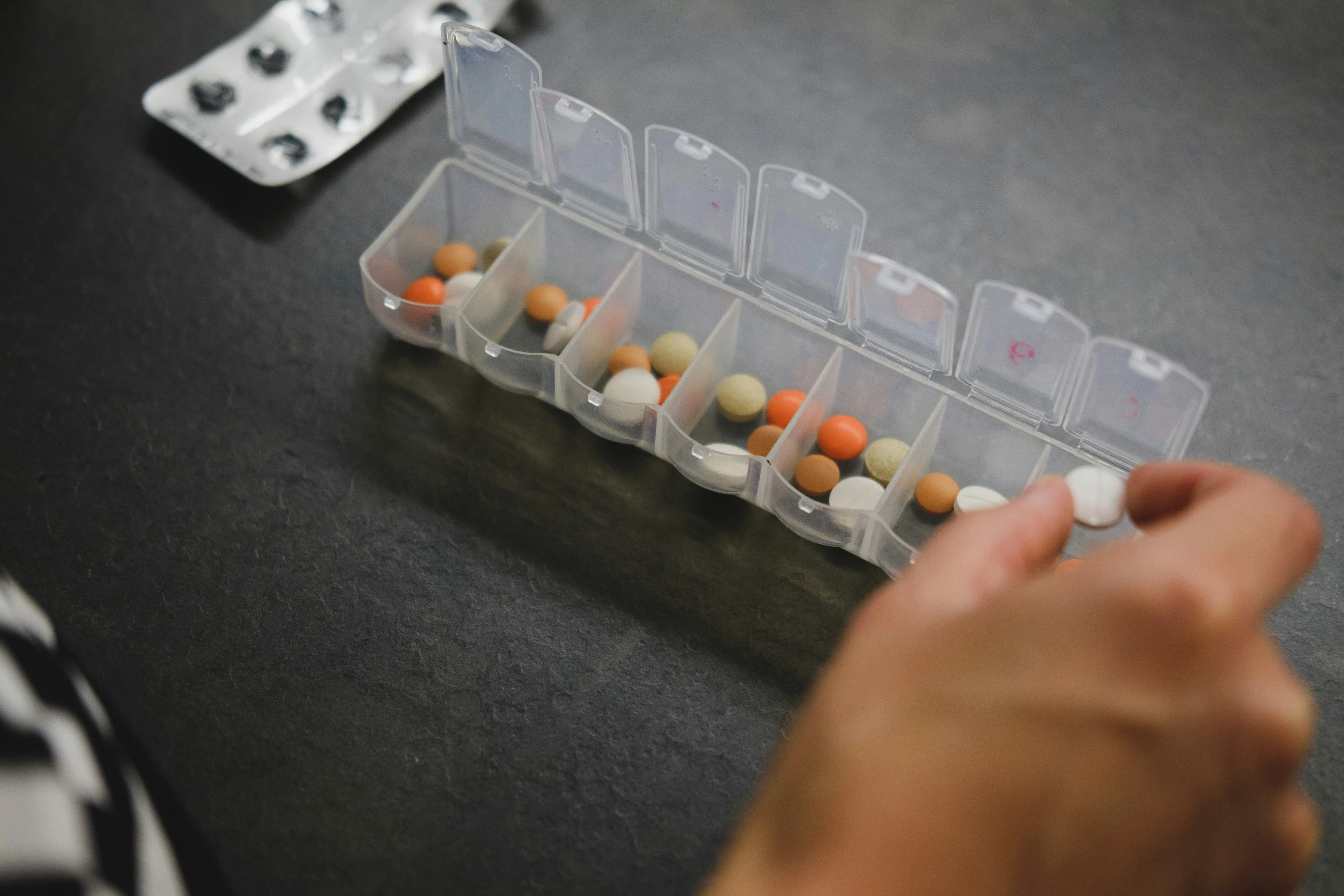 Hand filling a weekly pill organiser with tablets
